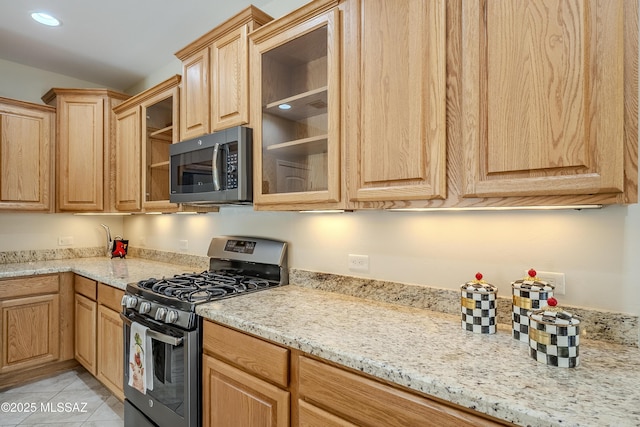 kitchen with stainless steel appliances, light stone countertops, and light tile patterned floors