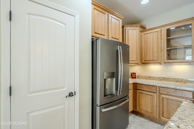 kitchen featuring stainless steel refrigerator with ice dispenser, light brown cabinetry, light stone countertops, and light tile patterned floors