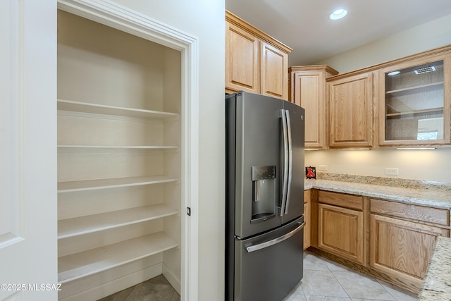 kitchen featuring light tile patterned floors, light stone counters, and stainless steel fridge with ice dispenser