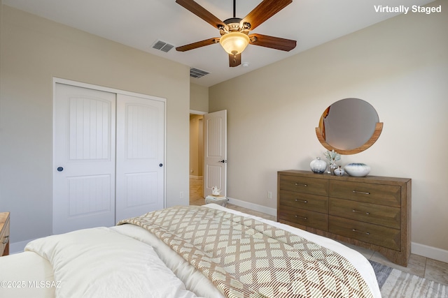 tiled bedroom with ceiling fan and a closet