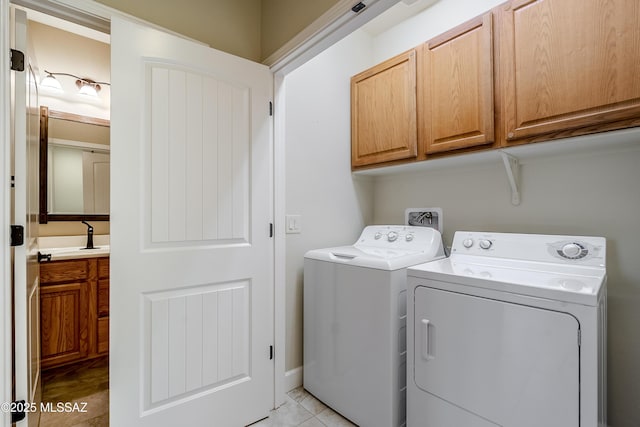 laundry room with cabinets, sink, washer and dryer, and light tile patterned floors