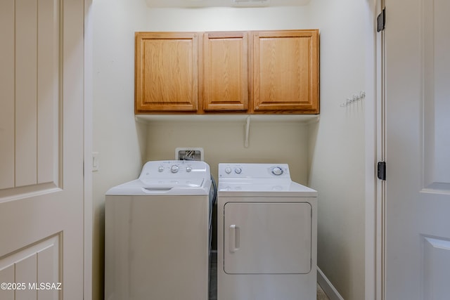 laundry room featuring washer and clothes dryer and cabinets