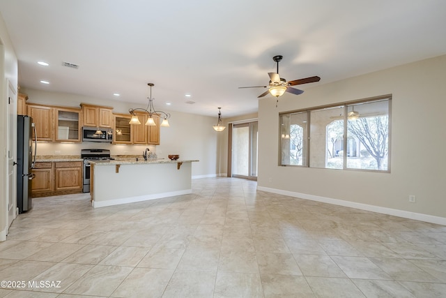 kitchen with light stone counters, appliances with stainless steel finishes, a kitchen breakfast bar, ceiling fan, and a kitchen island with sink