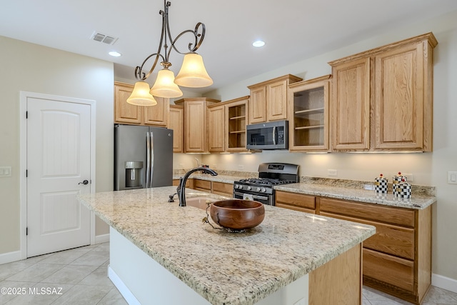 kitchen with light tile patterned flooring, stainless steel appliances, hanging light fixtures, and a center island with sink