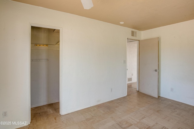 unfurnished bedroom featuring a walk in closet, a closet, and ceiling fan