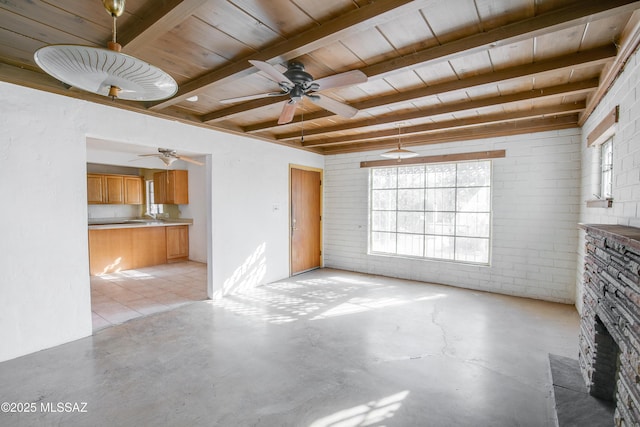 unfurnished living room with wooden ceiling, ceiling fan, a fireplace, beam ceiling, and brick wall