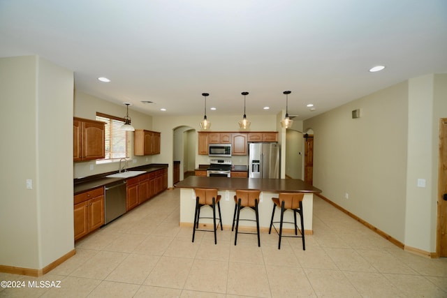 kitchen featuring sink, light tile patterned flooring, a center island, pendant lighting, and stainless steel appliances