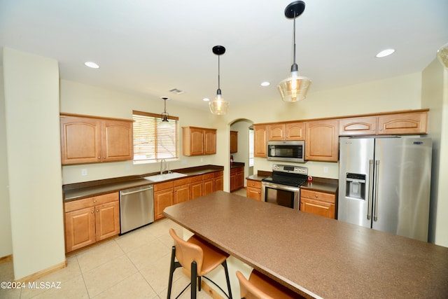 kitchen featuring sink, appliances with stainless steel finishes, light tile patterned floors, and decorative light fixtures