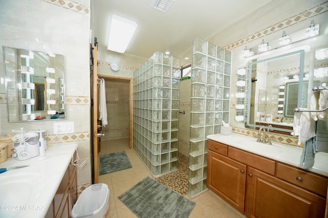 bathroom with tile patterned floors, a tile shower, tile walls, and vanity