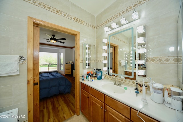 bathroom with tile walls, ceiling fan, vanity, and hardwood / wood-style floors