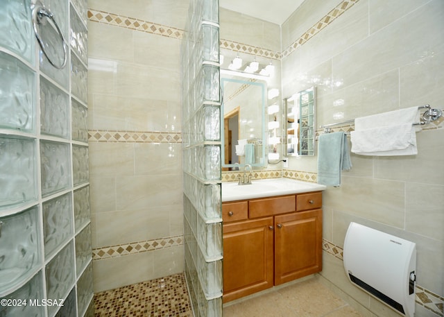 bathroom with tile patterned floors, a tile shower, tile walls, and vanity