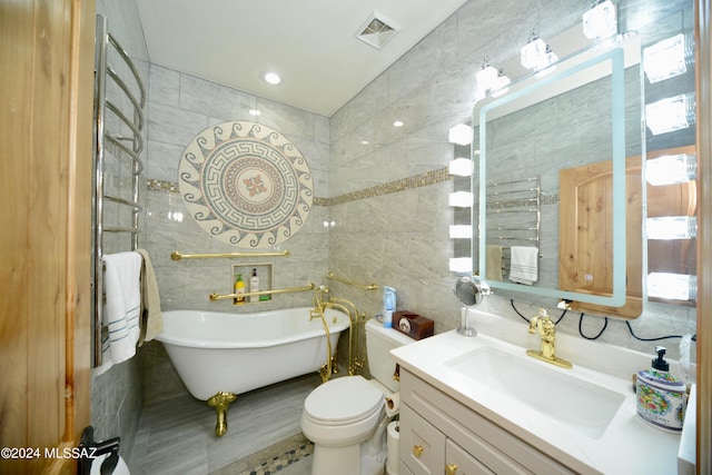 bathroom featuring toilet, vanity, a tub to relax in, and tile walls