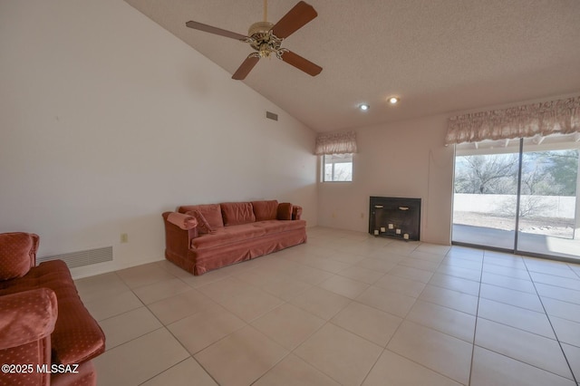 living room featuring ceiling fan, high vaulted ceiling, a textured ceiling, and light tile patterned floors