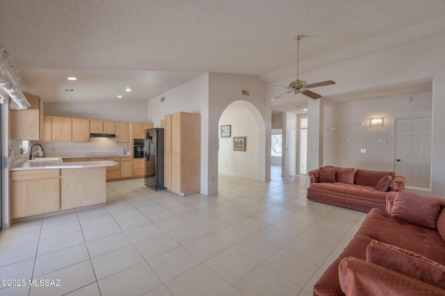 living room with light tile patterned flooring, sink, vaulted ceiling, a textured ceiling, and ceiling fan