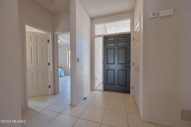 foyer entrance featuring a textured ceiling and light tile patterned floors