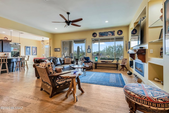 living area with light wood-type flooring, a fireplace, a ceiling fan, and recessed lighting