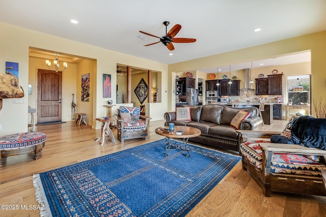 living area with recessed lighting, light wood-style flooring, visible vents, and ceiling fan with notable chandelier