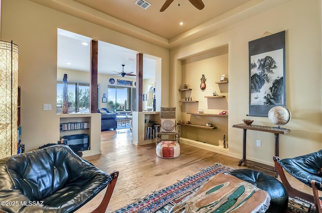 sitting room featuring visible vents, ceiling fan, baseboards, and wood finished floors