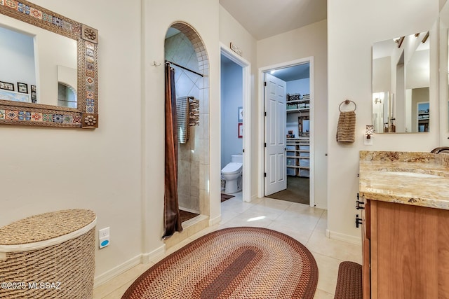 bathroom with baseboards, toilet, tile patterned flooring, vanity, and a shower stall