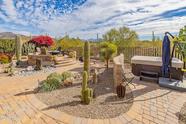 view of patio featuring a fire pit, fence, a mountain view, and a hot tub