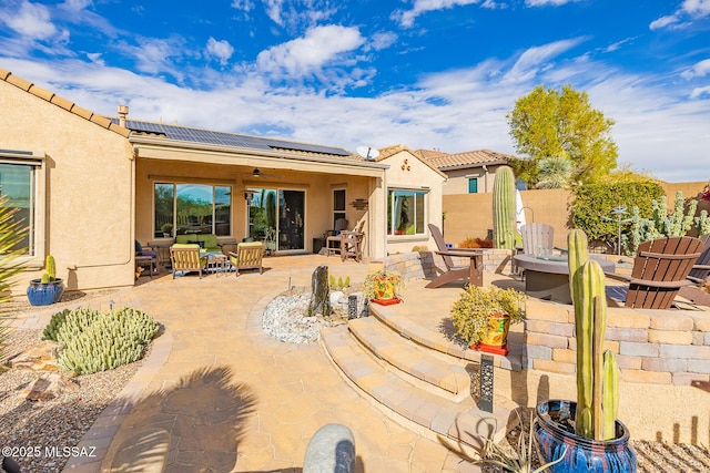 rear view of house with solar panels, a tile roof, fence, a patio area, and stucco siding