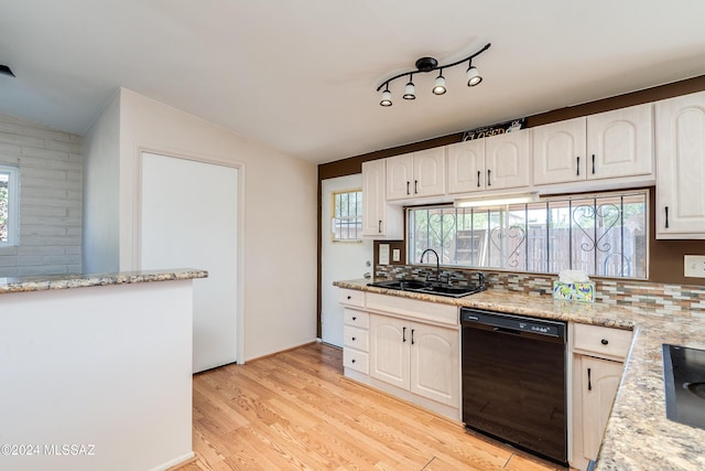 kitchen with a healthy amount of sunlight, light hardwood / wood-style floors, lofted ceiling, and black dishwasher