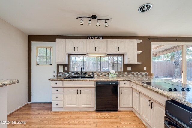 kitchen featuring light wood-type flooring, sink, a wealth of natural light, and black appliances