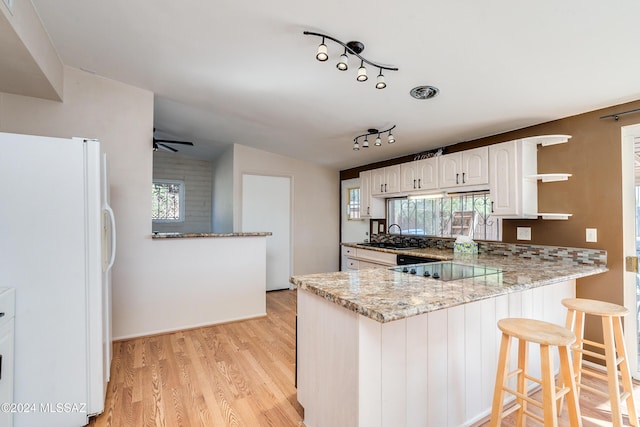 kitchen with kitchen peninsula, white cabinets, white fridge, and a healthy amount of sunlight