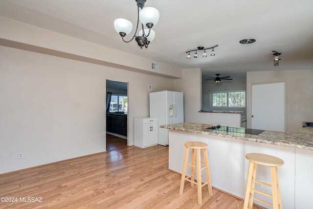 kitchen with a kitchen breakfast bar, white refrigerator with ice dispenser, black electric cooktop, white cabinets, and light wood-type flooring