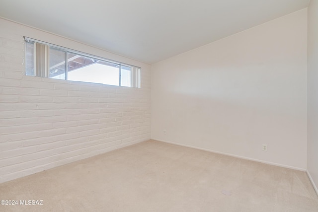 spare room with light carpet and brick wall