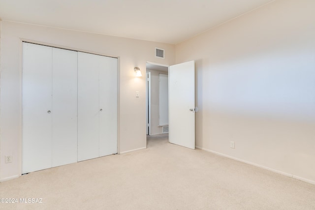 unfurnished bedroom featuring a closet and light colored carpet