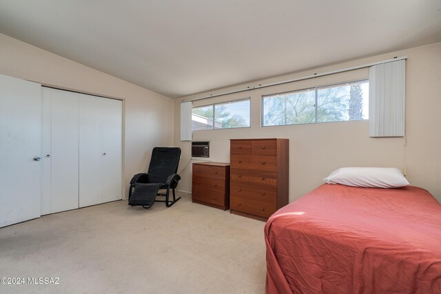 bedroom with light colored carpet, an AC wall unit, a closet, and lofted ceiling