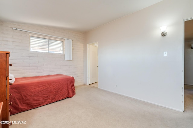 bedroom featuring light carpet and brick wall