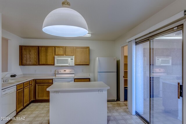 kitchen with a kitchen island, white appliances, sink, and washer / clothes dryer