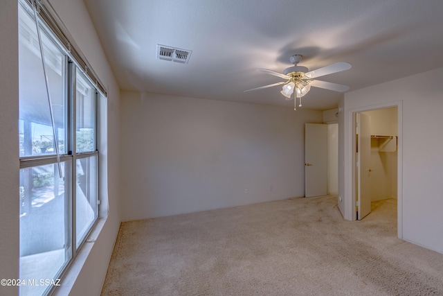 carpeted spare room featuring ceiling fan and a healthy amount of sunlight