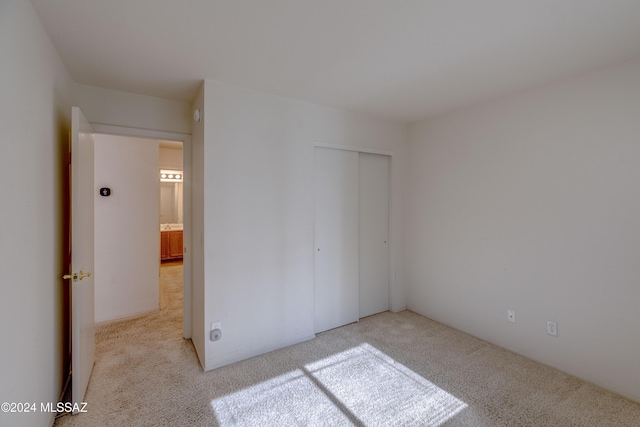 unfurnished bedroom with light colored carpet and a closet