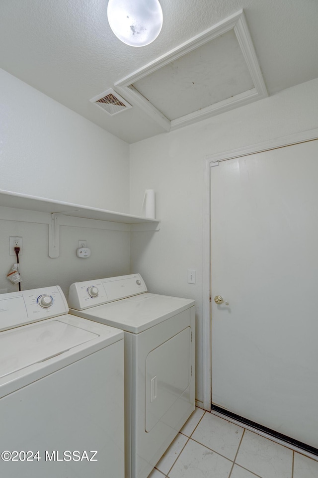 laundry room featuring light tile patterned floors, a textured ceiling, and washing machine and clothes dryer