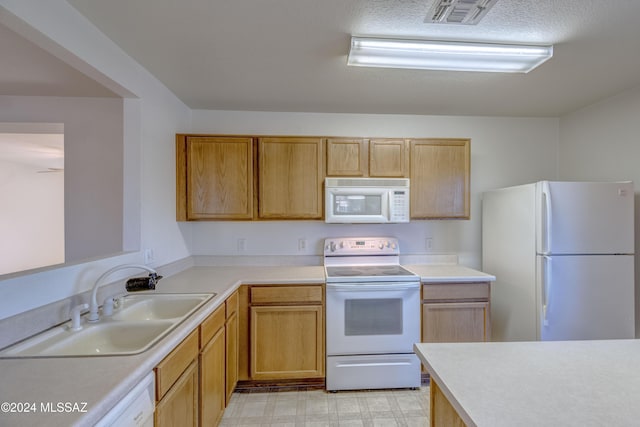 kitchen with a textured ceiling, sink, white appliances, and light brown cabinets