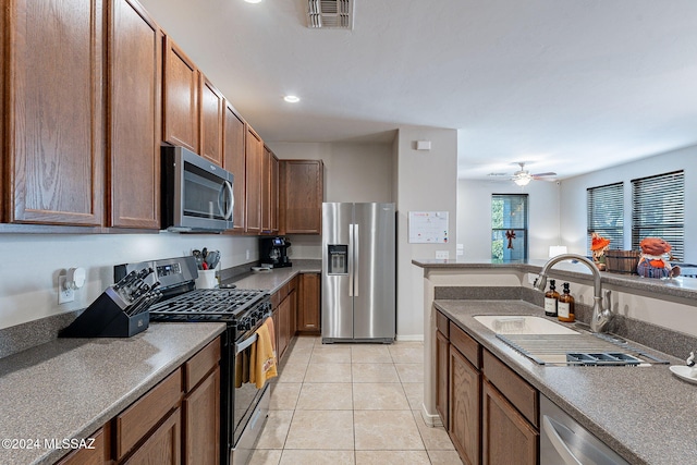 kitchen with appliances with stainless steel finishes, light tile patterned floors, ceiling fan, and sink