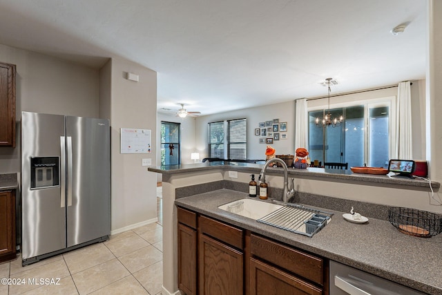 kitchen featuring sink, stainless steel appliances, pendant lighting, light tile patterned floors, and ceiling fan with notable chandelier