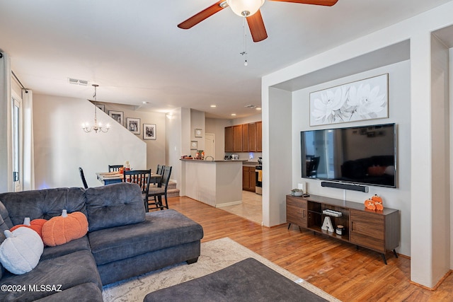 living room featuring light hardwood / wood-style floors and ceiling fan with notable chandelier