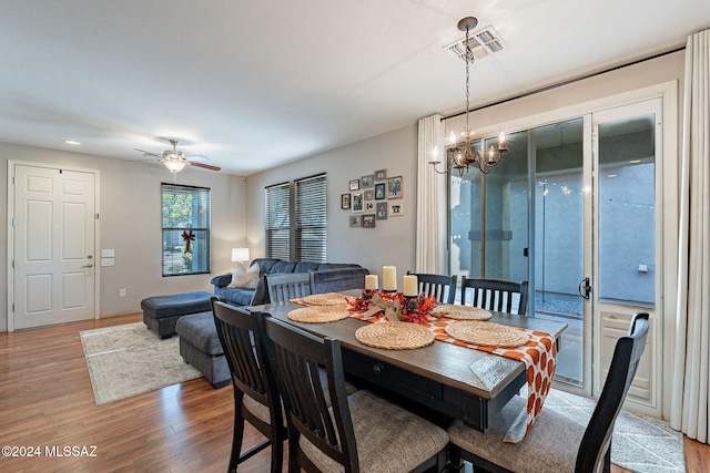 dining area with hardwood / wood-style floors and ceiling fan with notable chandelier