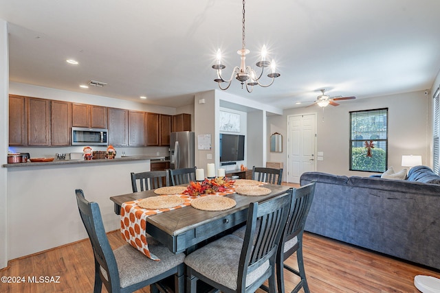 dining area featuring ceiling fan with notable chandelier and light hardwood / wood-style flooring