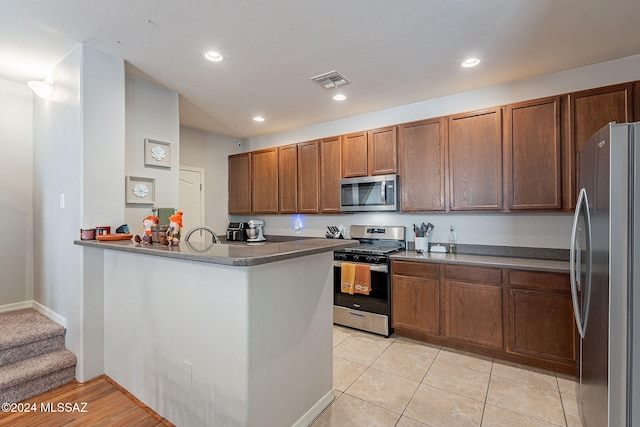 kitchen with kitchen peninsula, light tile patterned flooring, and stainless steel appliances