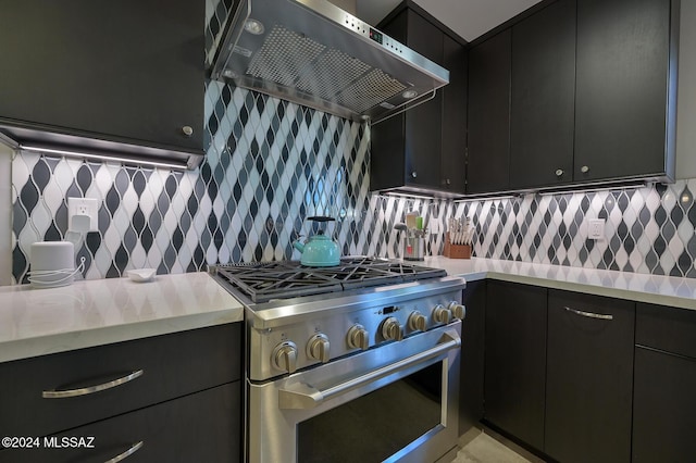 kitchen featuring backsplash, wall chimney range hood, and high end stainless steel range oven