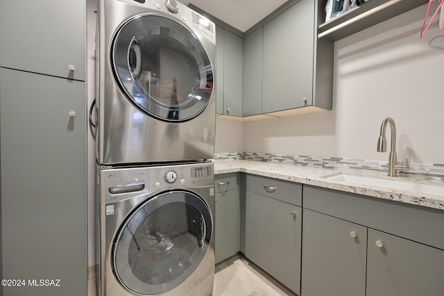 washroom with stacked washing maching and dryer, cabinets, and sink