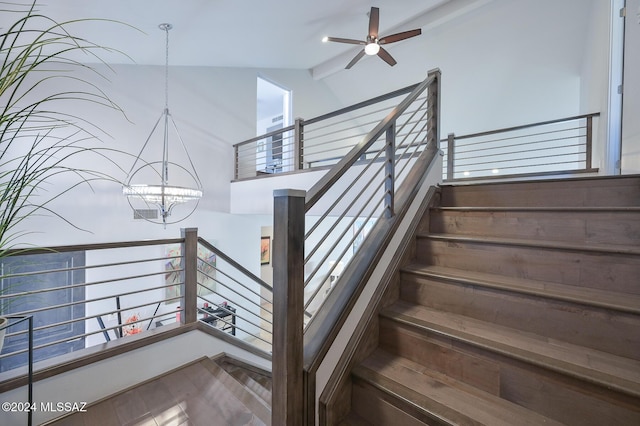 stairway featuring ceiling fan with notable chandelier