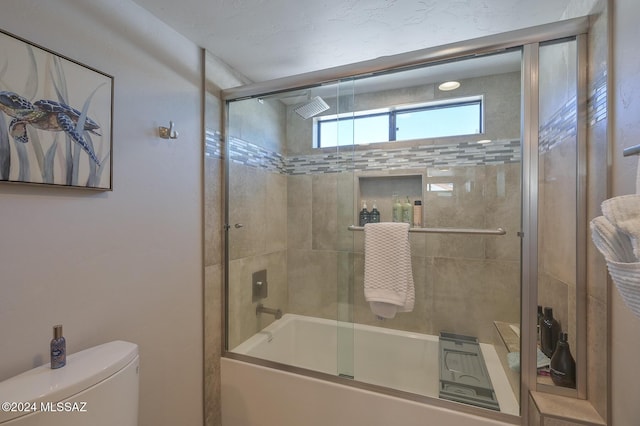 bathroom featuring toilet and bath / shower combo with glass door