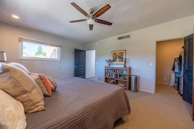 bedroom with ceiling fan, a walk in closet, a closet, and light colored carpet