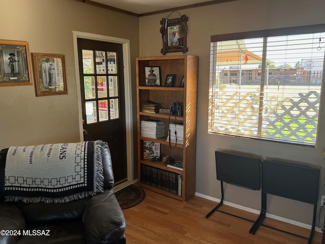 living area with hardwood / wood-style floors, a healthy amount of sunlight, and ornamental molding